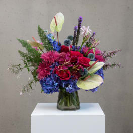 Colorful mixed bouquet in a glass vase with roses, hydrangeas, and anthuriums