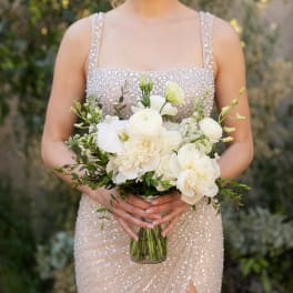 Bride holding a white bouquet in a clear glass vase