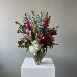 Tall mixed bouquet in a clear glass vase with pink lilies and white hydrangea