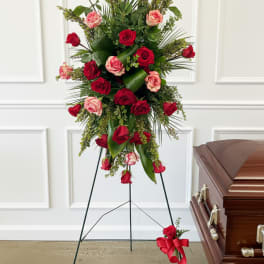 Standing red and pink rose spray beside a casket