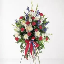 Standing floral spray with red, white, and blue flowers on a wire easel