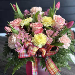 Pink and yellow bouquet in a magenta vase with plaid ribbon