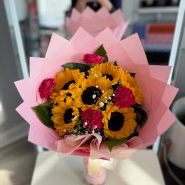 Bouquet of sunflowers and pink carnations wrapped in pink paper