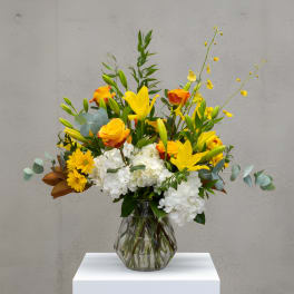 Yellow lilies and roses with white hydrangeas in a glass vase