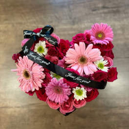 Heart-shaped bouquet of pink gerberas and red roses with a black ribbon