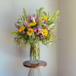 Mixed bouquet of pink and yellow flowers in a clear glass vase