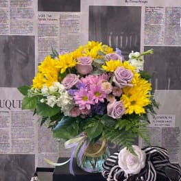Bouquet of yellow daisies and lavender roses in a glass vase
