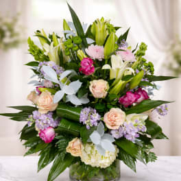 Mixed bouquet of lilies, roses, and lavender flowers in a glass vase