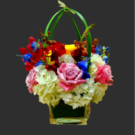 Colorful flower basket with roses, hydrangeas, and orchids in a glass vase