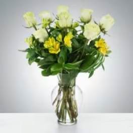 Glass vase of white roses and yellow alstroemeria in a rounded mixed bouquet