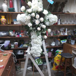 White floral standing cross on a white easel