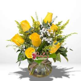Yellow roses arranged in a round glass vase with white filler flowers