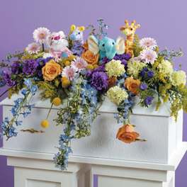Colorful floral arrangement with plush animals on a white casket
