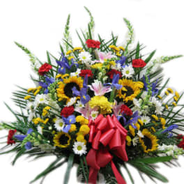 Large mixed floral spray with sunflowers, daisies, and a red bow