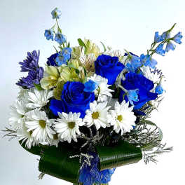 Blue roses and white daisies in a glass vase with ribbon