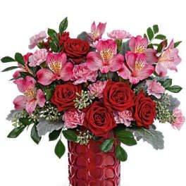 Bouquet of red roses and pink alstroemeria in a red glass vase