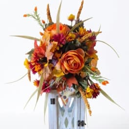 Autumn floral arrangement with orange blooms in a white lantern