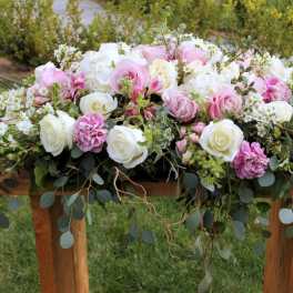Large pink and white floral arrangement with roses on a wooden table
