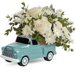 White roses and daisies arranged in a turquoise truck planter