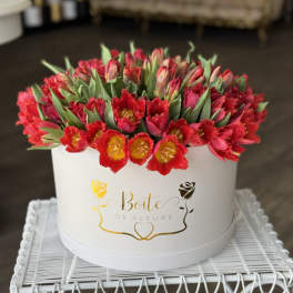 Round box of red tulips with green leaves