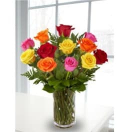Mixed-color roses arranged in a clear glass vase on a white table