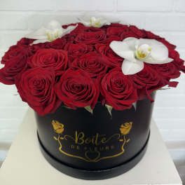 Red roses and white orchids arranged in a black round box