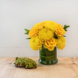 Yellow roses and chrysanthemums in a green glass vase