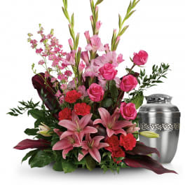 Pink lilies and roses arranged beside a silver urn