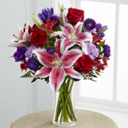 Bouquet of red roses and pink lilies in a clear glass vase