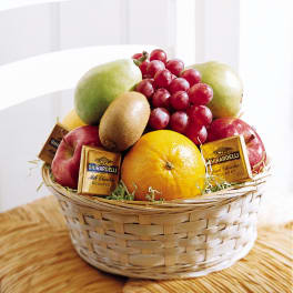 Gift basket filled with assorted fresh fruit and wrapped chocolate squares in a woven light-colored basket