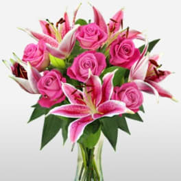 Pink roses and lilies arranged in a clear glass vase