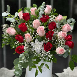 Bouquet of red and pink roses in a white box with a jeweled flower accent