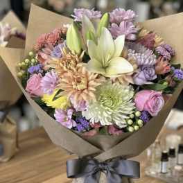 Mixed pastel bouquet with lilies and roses wrapped in brown paper