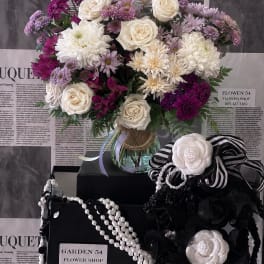 Bouquet of white and purple flowers in a glass vase with black-and-white ribbon accents