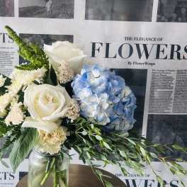 Bouquet of white roses, blue hydrangea, and cream flowers in a glass jar