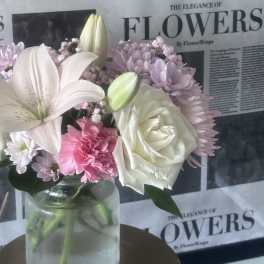 Bouquet of white lilies, roses, and pink flowers in a glass vase