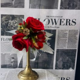Red rose bouquet in a gold trumpet vase with silver ribbon accents
