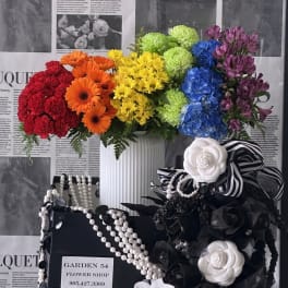 Colorful mixed flower arrangement in a white vase with black-and-white ribbon accents