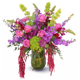 Pink roses and purple flowers in a green glass vase