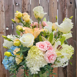 Pastel mixed bouquet in a glass vase with roses, lilies, hydrangeas, and lisianthus