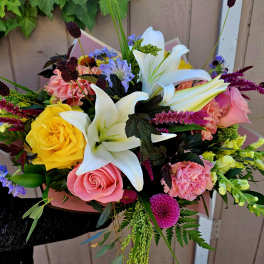 Mixed bouquet with white lilies, pink and yellow roses, and bright accent flowers