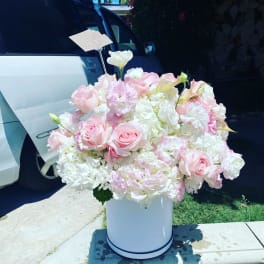 Large pastel pink and white flower arrangement in a white hatbox-style container