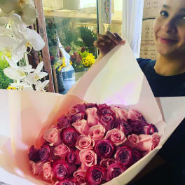 Large hand-tied bouquet of pink and purple roses wrapped in pale pink paper