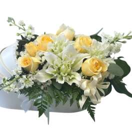 Yellow roses and white flowers in a white hatbox with a ribbon bow