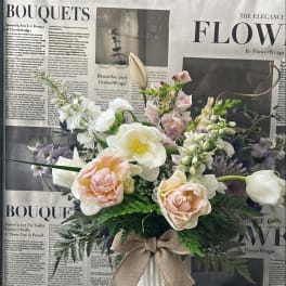 Bouquet of pastel flowers in a white vase with a burlap bow
