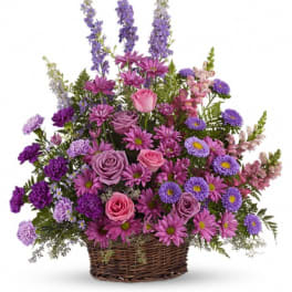 Purple and pink mixed flower arrangement in a wicker basket