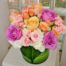 Bouquet of pink, purple, and peach roses in a green vase