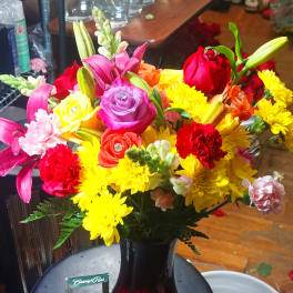 Colorful bouquet of roses, lilies, and chrysanthemums in a red vase