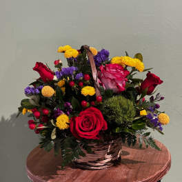 Basket arrangement with red roses, yellow mums, and purple filler flowers