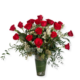 Red roses arranged in a clear glass vase with white filler flowers